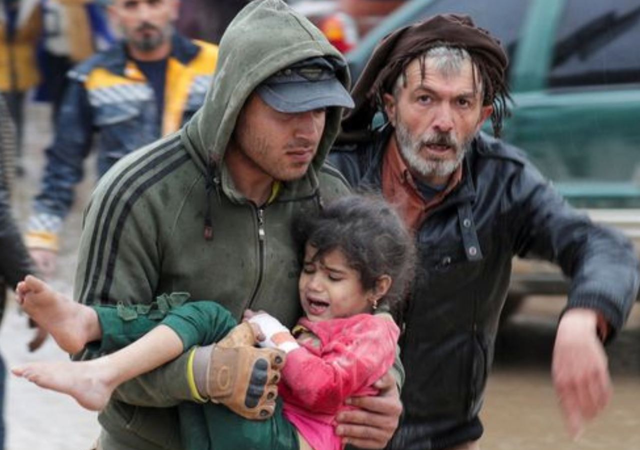 Two men carrying a child after the 2023 earthquake in Turkey and Syria